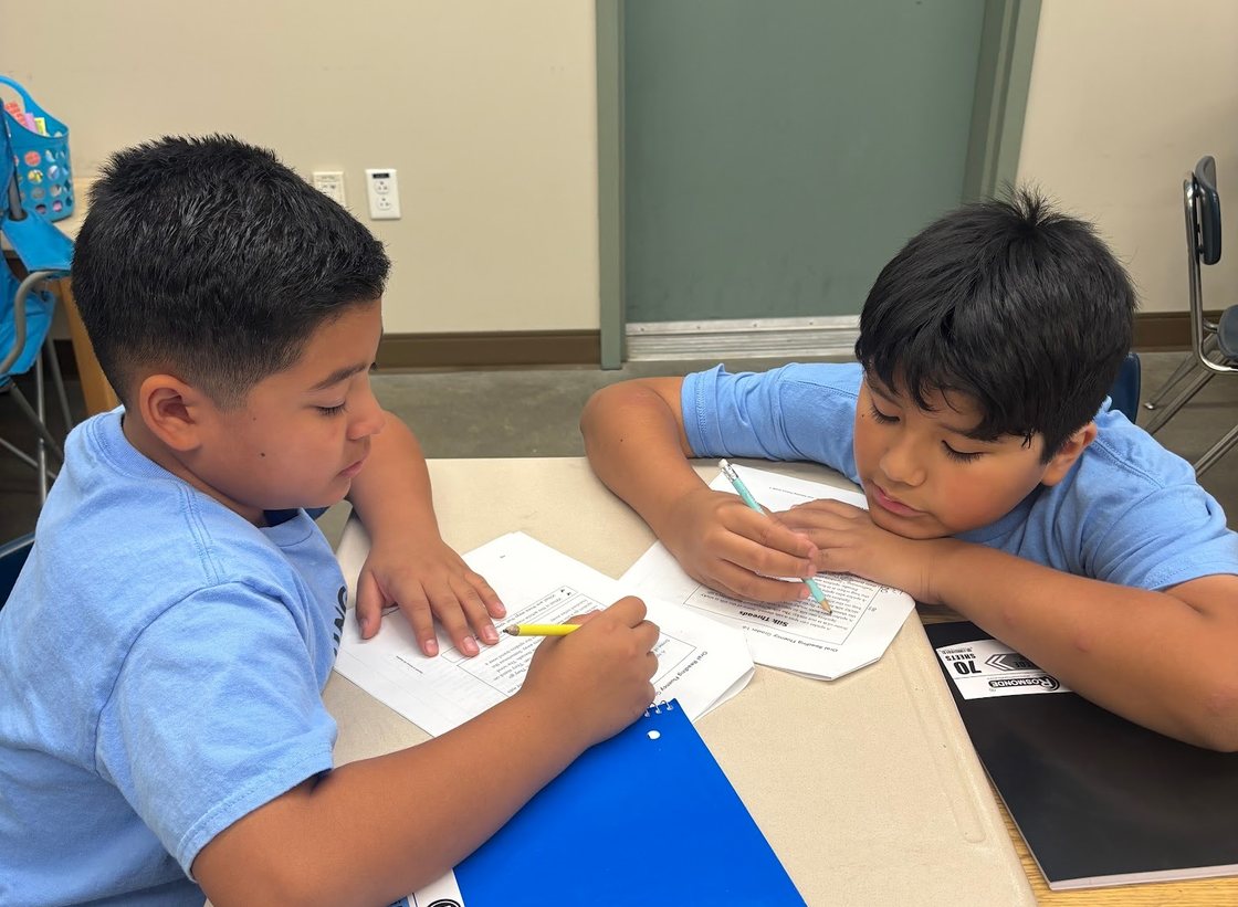 Two Learning Academy students working side by side on a writing assignment