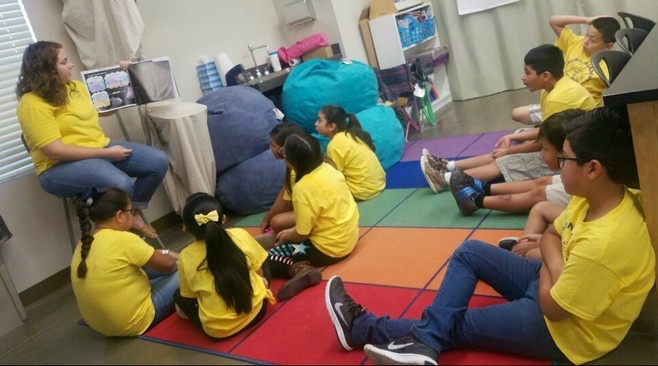 Reading Academy students sitting in a circle on the floor for story time