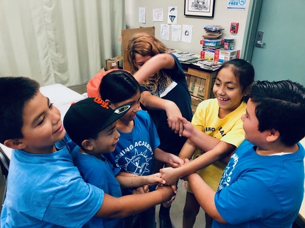 Learning Academy students and staff joining hands in a circle, 2019