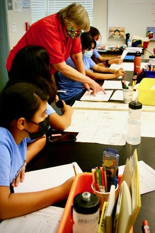 A BASIC teacher helping Learning Academy students at their desks