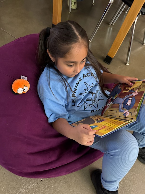 A Learning Academy student reading a picture book on a beanbag chair