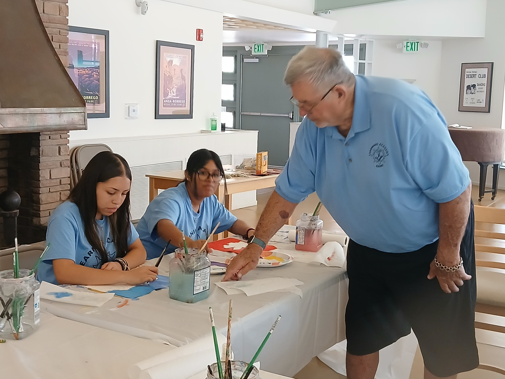 A BASIC staff member helping two Learning Academy students at an art table