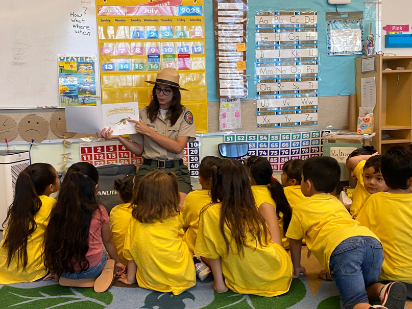 An Anza-Borrego Desert State Park ranger reading a picture book to TK Academy students seated on the classroom floor