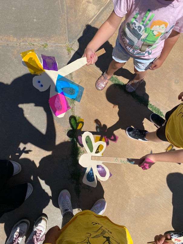 TK Academy students outside holding hand-made paper wind spinners in the sunshine