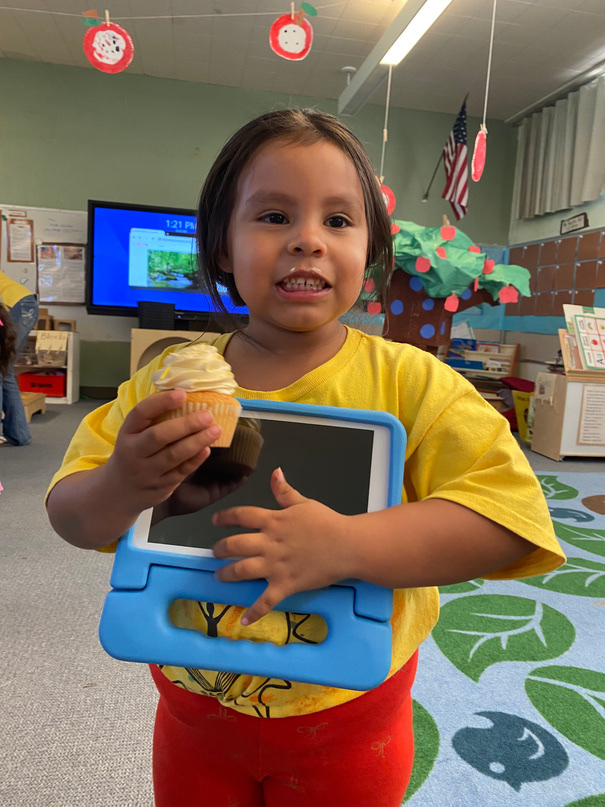 A TK Academy student holding her ApSeed learning tablet and an ice cream treat