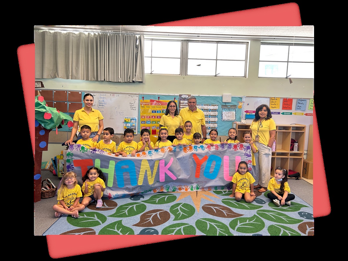 The TK Academy 2025 class and staff holding a hand-painted THANK YOU banner in their classroom