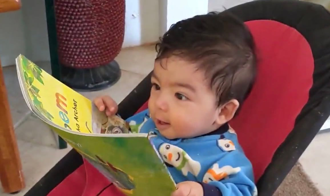 An infant holding an illustrated board book, from BASIC&rsquo;s earliest-years reading program
