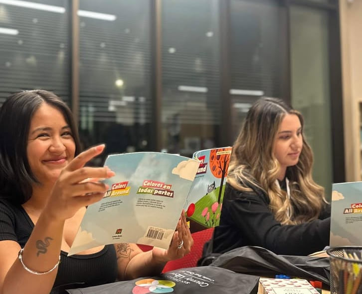 Two volunteers preparing bilingual English and Spanish picture books for BASIC&rsquo;s early literacy program