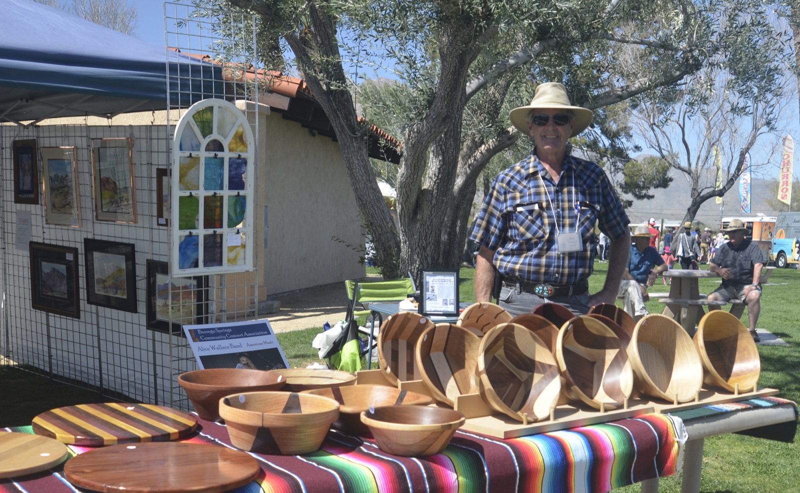 A row of turned wooden bowls on a serape-covered table in an artist's tent at Circle of Art