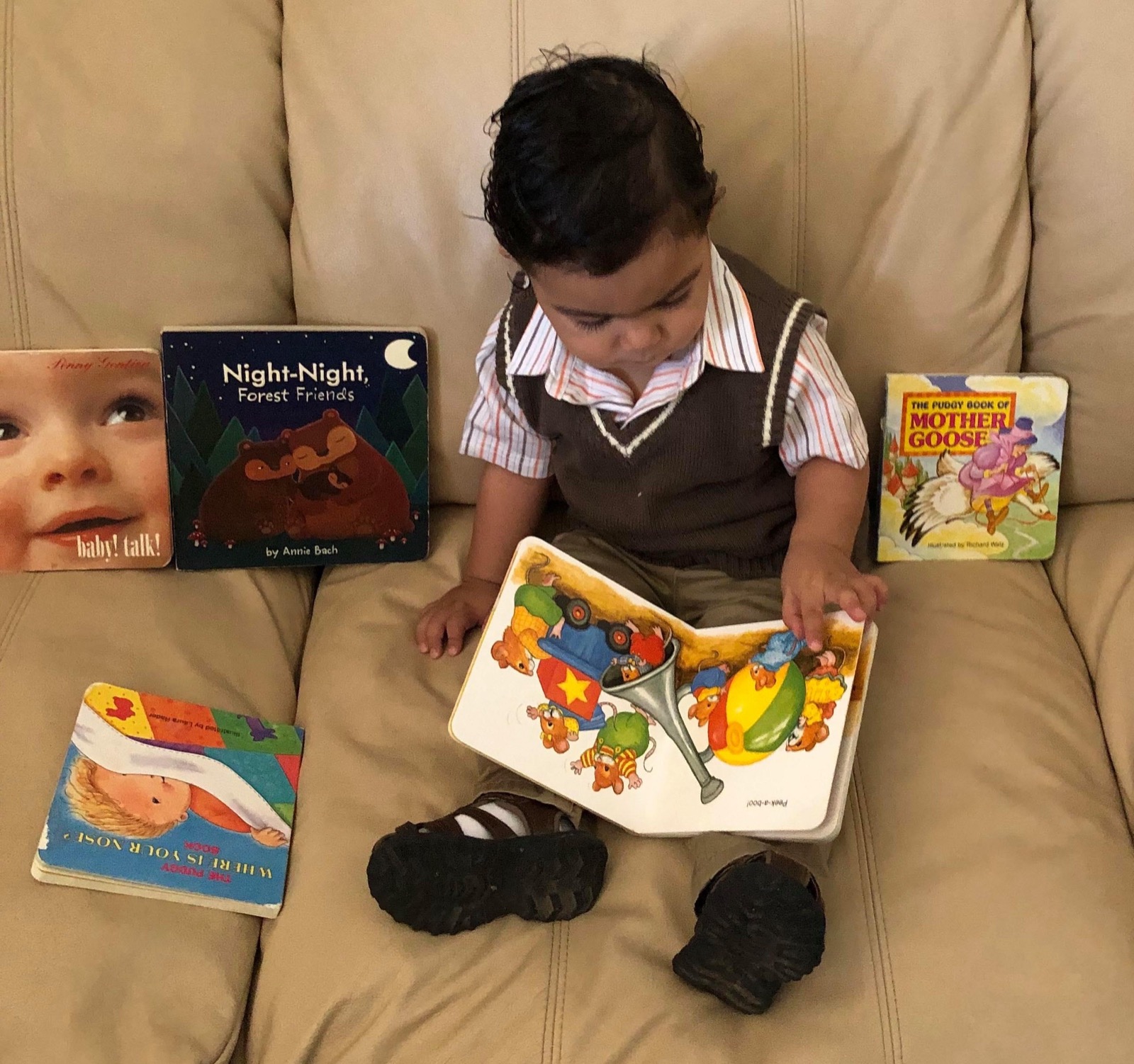 Dylan Garcia as a toddler on a sofa turning the pages of a board book, with five more Imagination Library board books arranged around him