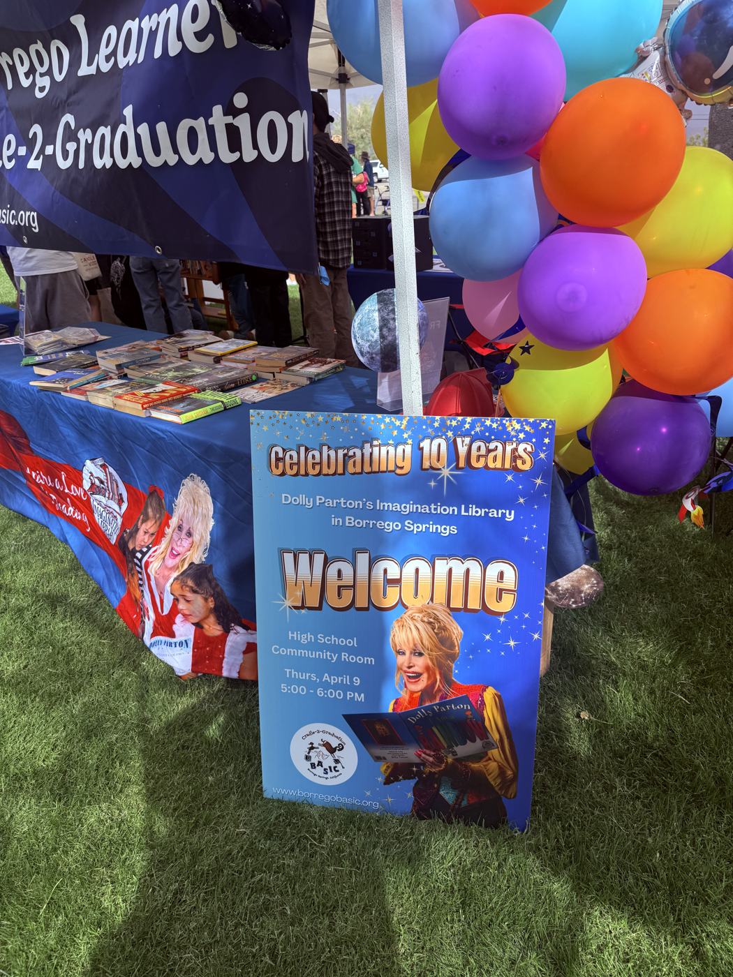 The Celebrating 10 Years Dolly Parton's Imagination Library in Borrego Springs welcome sign at the end of the BASIC booth, with a bunch of balloons
