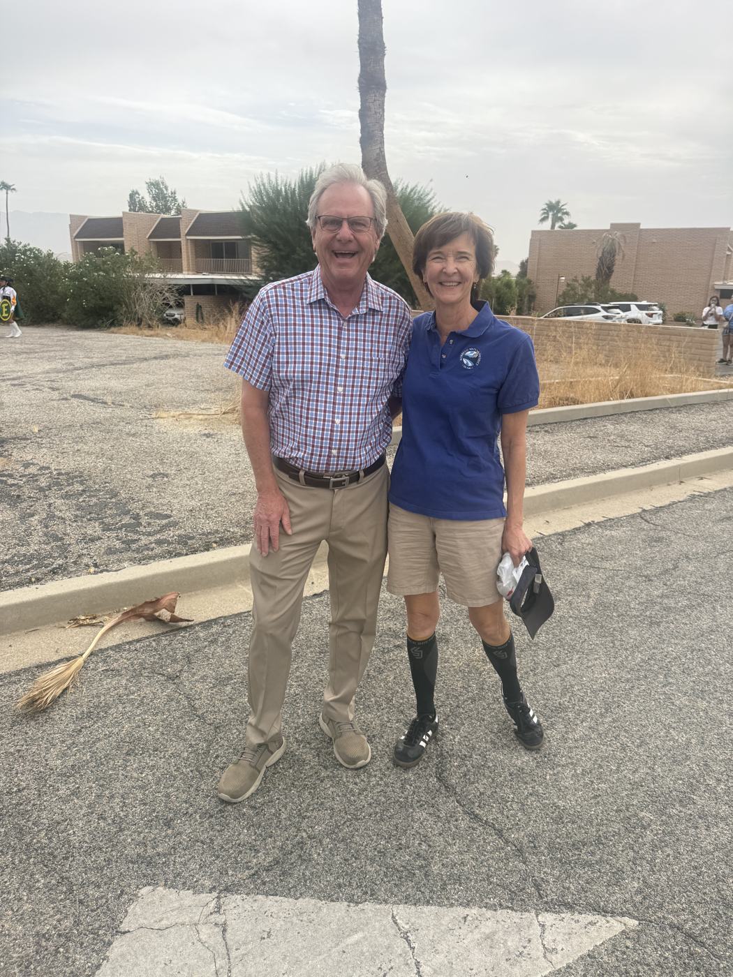 San Diego County Supervisor Jim Desmond in a plaid shirt standing with Tammy Baker of the Borrego Water District in a blue polo, both smiling, in the parade staging area